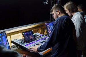 Student training in an audio engineering studio learning recording and mixing techniques.